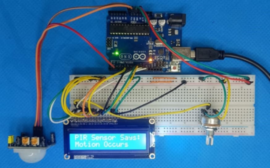 Assembled motion detection system using Arduino, PIR sensor, and LCD on a breadboard.